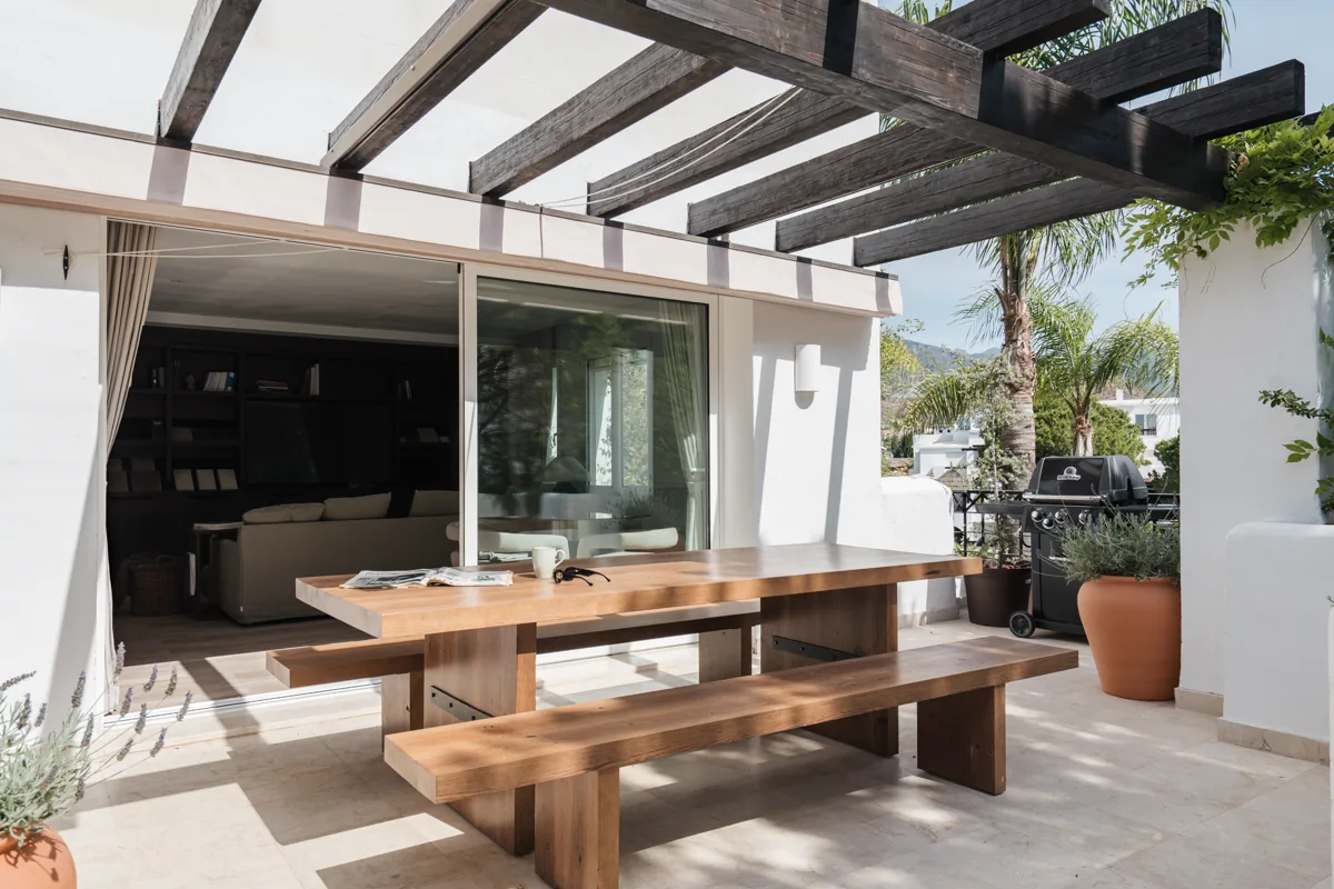 A covered terrace with a long dining table, at one of the managed homes