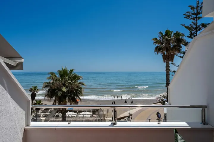 View from the balcony of the La Roca beach studio in Torremolinos, over palm trees, the promenade and the beach
