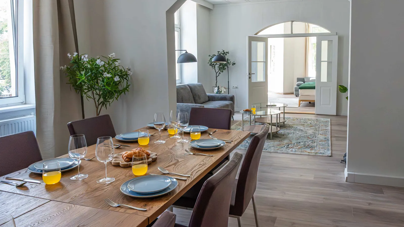 Dining table laid for breakfast in the Ottakring duplex, with an arched opening to the living room beyond