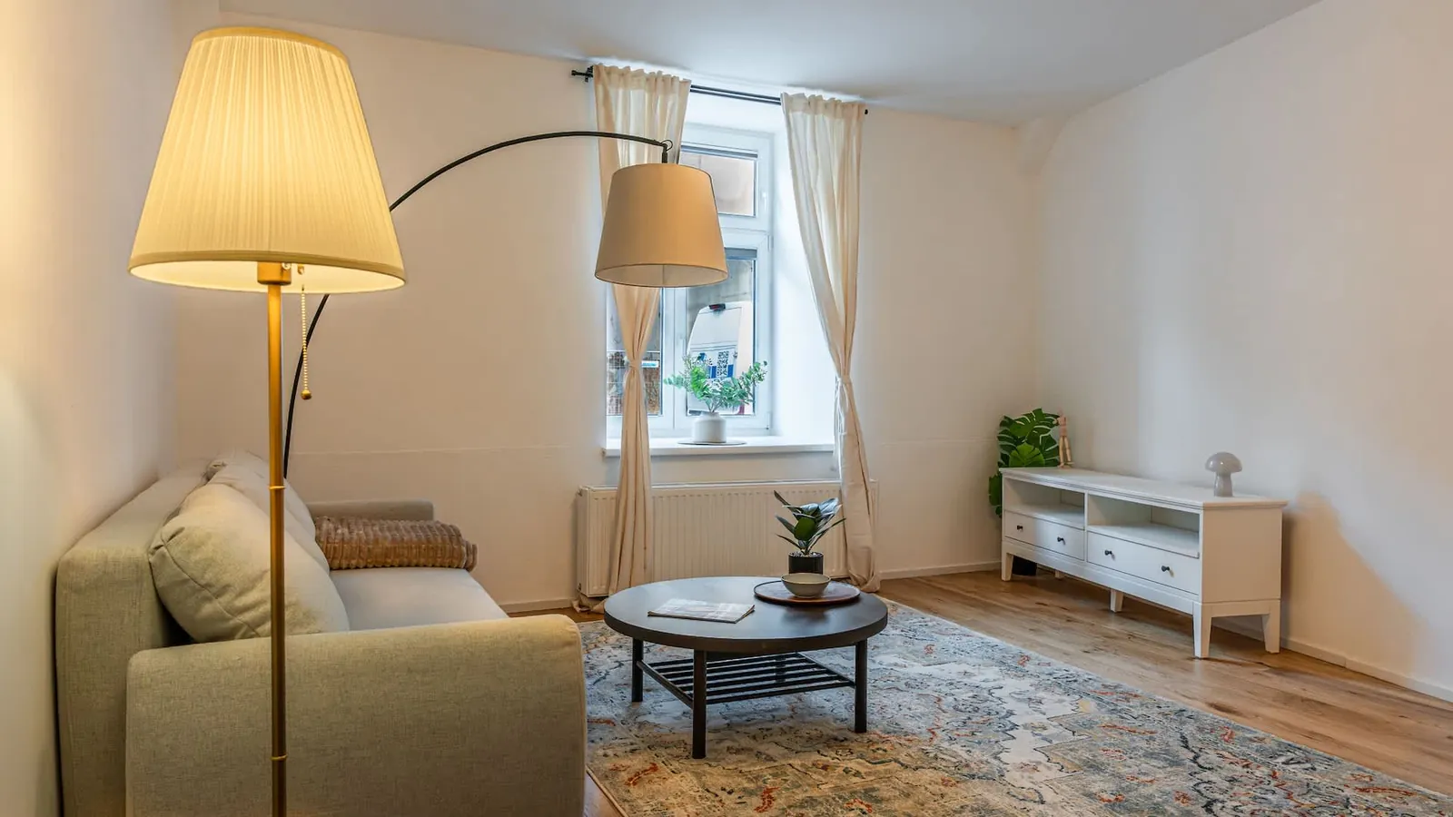 Living room of the apartment in the 3rd district, with a sofa, a floor lamp and tall windows