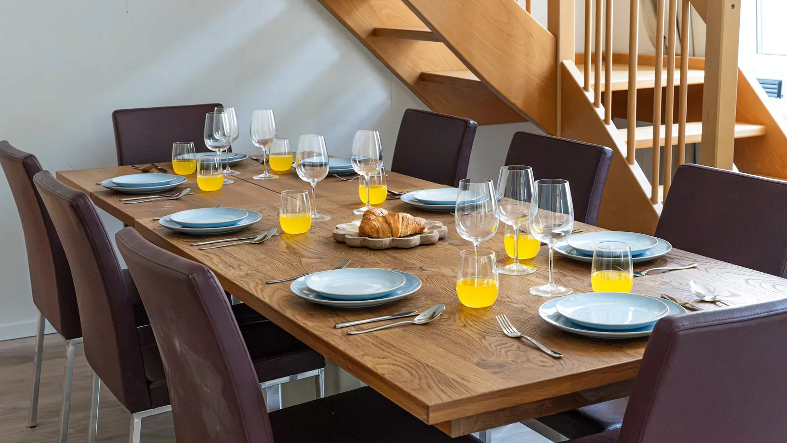 Long dining table and the wooden staircase to the upper floor of the Ottakring duplex
